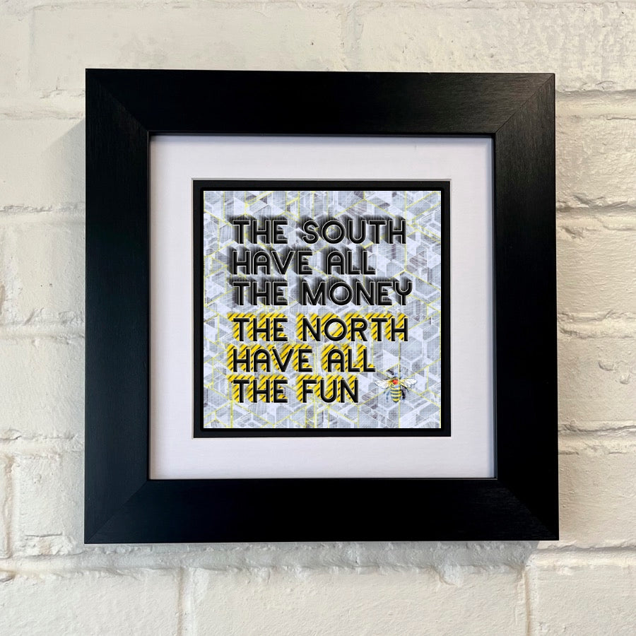 A framed print with the text 'THE SOUTH HAVE ALL THE MONEY THE NORTH HAVE ALL THE FUN' on GREY background, displayed against a white brick wall.