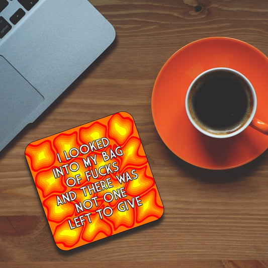 A square coaster with a orange and yellow design and text that reads 'I LOOKED INTO MY BAG OF FUCKS AND THERE WAS NOT ONE LEFT TO GIVE'