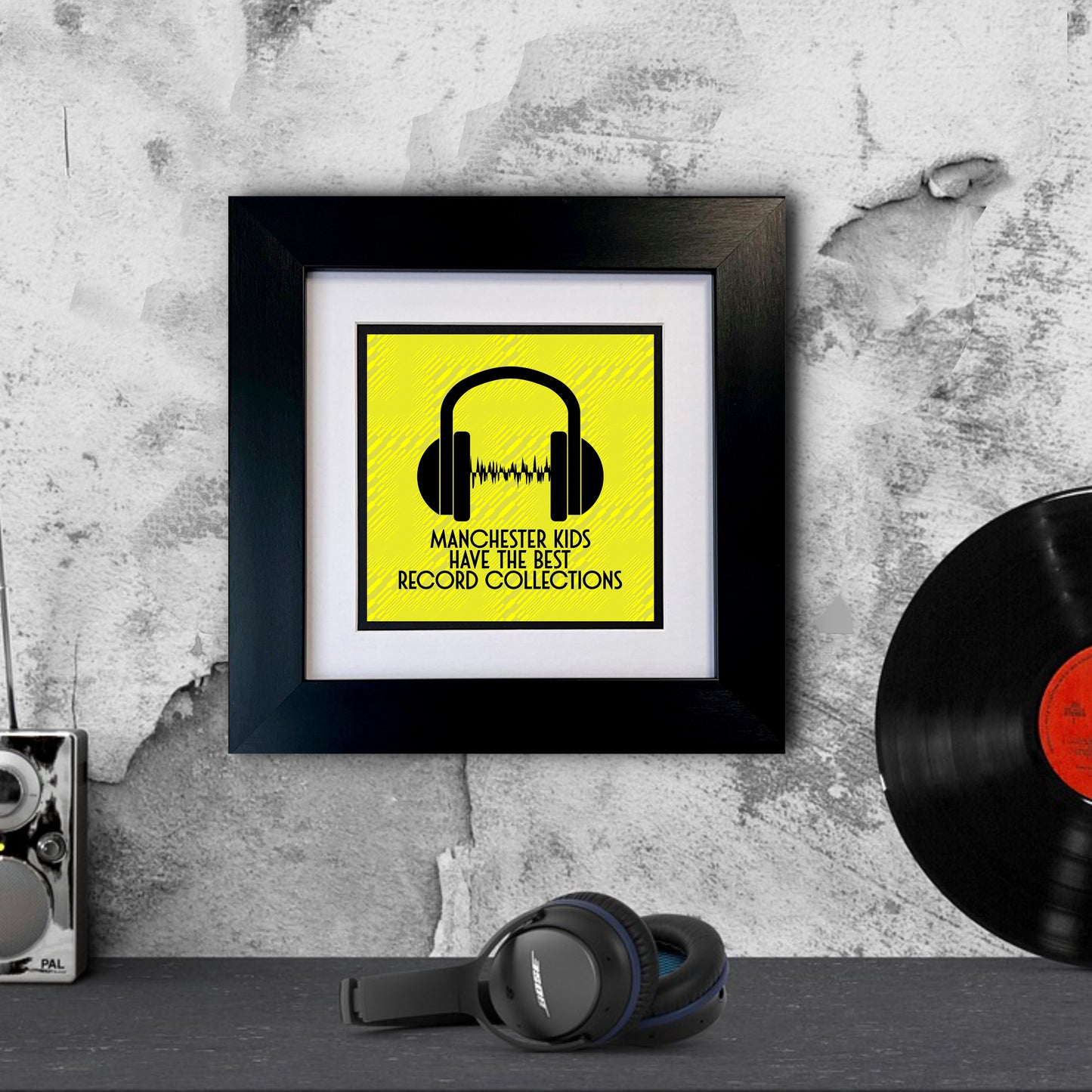 A black square frame with a yellow background, featuring MANCHESTER KIDS HAVE THE BEST RECORD COLLECTIONS text and a graphic of headphones.