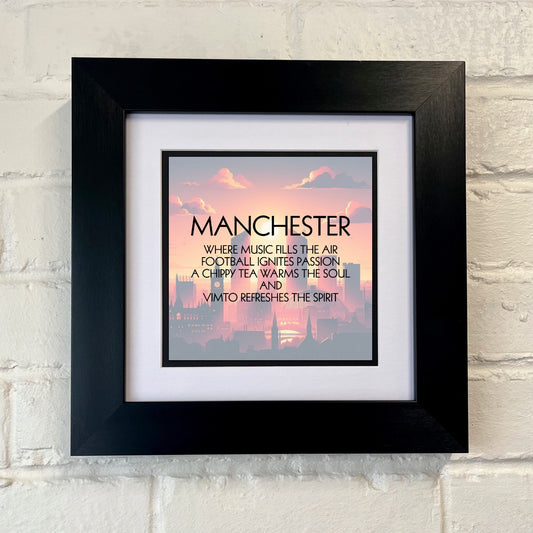 A framed print with a black frame displaying a Manchester quote, set against a white wall.