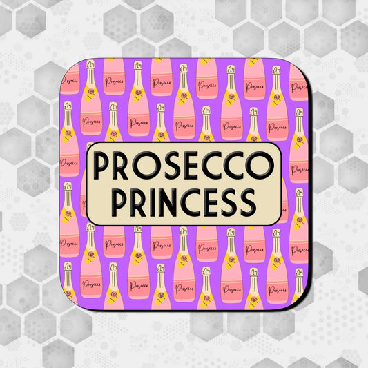 Coaster featuring a pattern of pink and peach Prosecco bottles on a purple background, with a rounded beige box in the center displaying bold black text that reads ‘Prosecco Princess