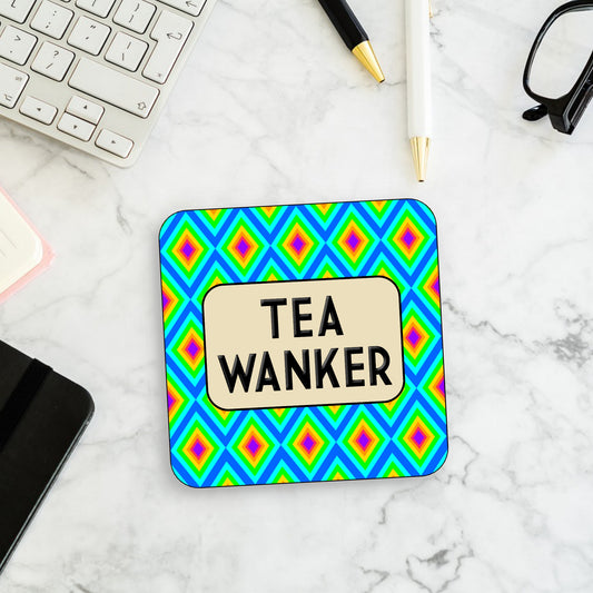Colorful coaster with 'TEA WANKER' text on a marble surface with office items.