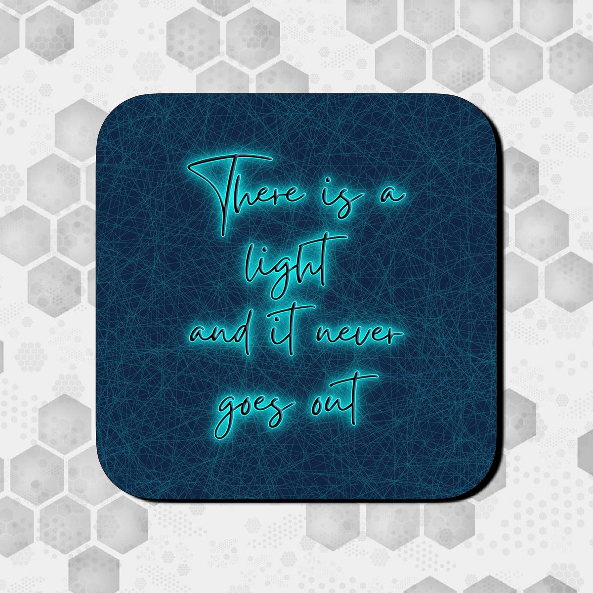A square coaster with a blue background featuring the text 'There is a light and it never goes out' in a BRIGHT BLUE font. THE SMITHS LYRICS