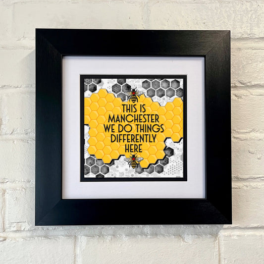 'THIS IS MANCHESTER WE DO THINGS DIFFERENTLY HERE' with a Manchester bee and a patterned background.