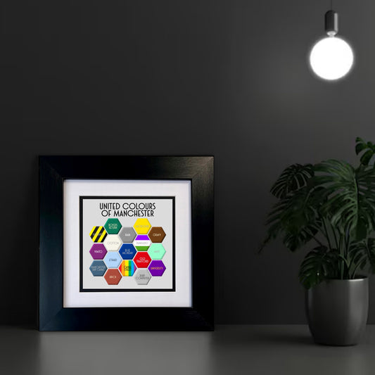 A colourful FRAMED print titled 'UNITED COLOURS OF MANCHESTER', featuring a honeycomb pattern with different colours and text elements representing various aspects of Manchester.