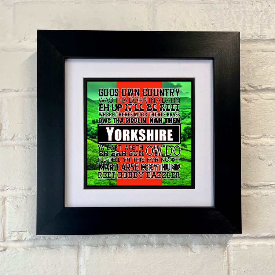 A framed print with a black frame displaying a colorful text-based artwork related to Yorkshire sayings.