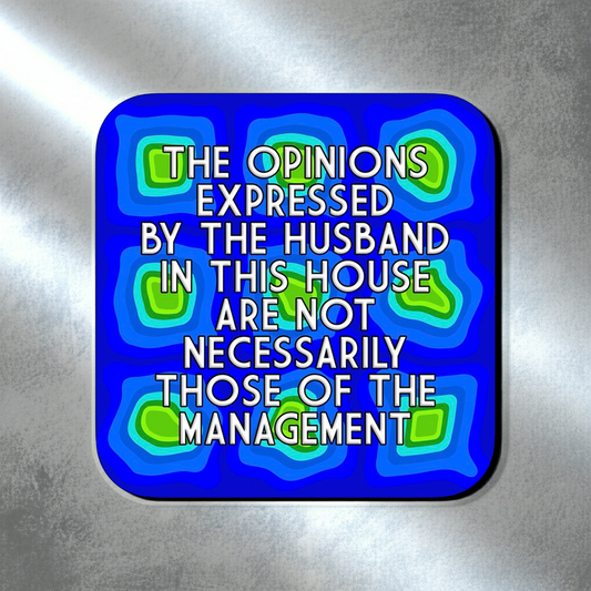 Coaster with a blue abstract layered pattern featuring green and teal geometric shapes, overlaid with bold centered text that reads ‘The opinions expressed by the husband in this house are not necessarily those of the management