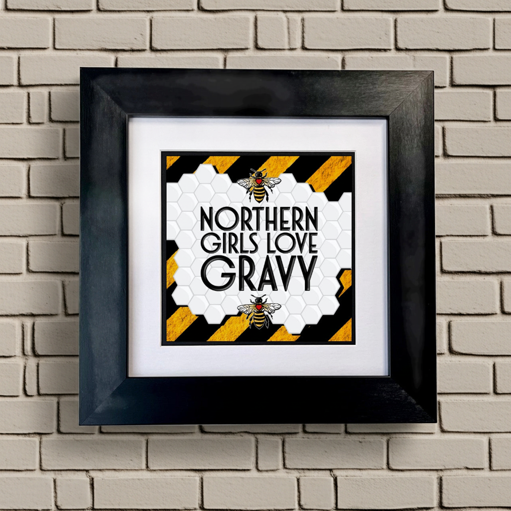 Framed artwork with 'Northern Girls Love Gravy' text on a brick wall background