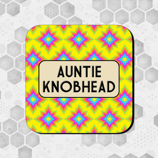 A square coaster with a colorful geometric pattern and the text 'AUNTIE KNOBHEAD' in bold letters.