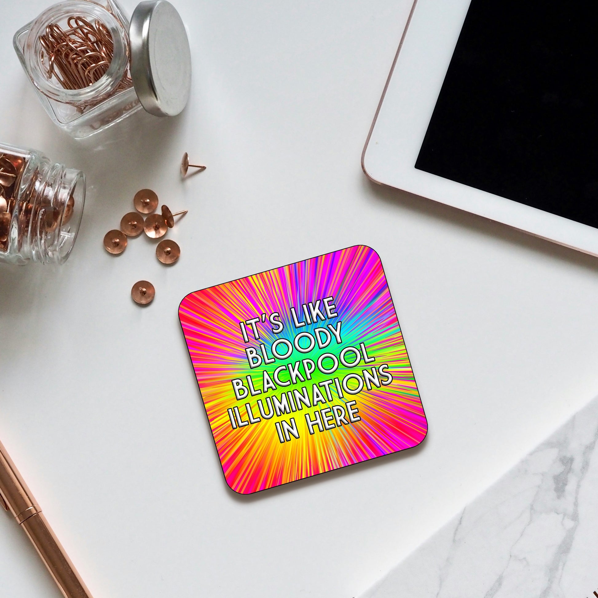 Coaster with a bright rainbow burst background radiating from the center, featuring bold text that reads ‘It’s like bloody Blackpool illuminations in here