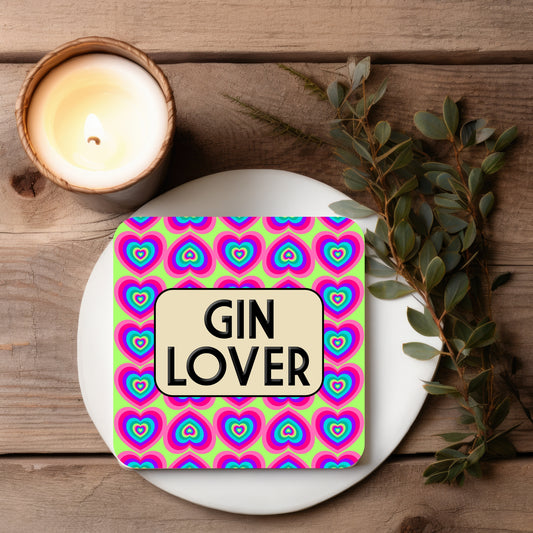 Coaster with 'Gin Lover' text on a colorful heart pattern, placed on a wooden surface with a candle and leaves.
