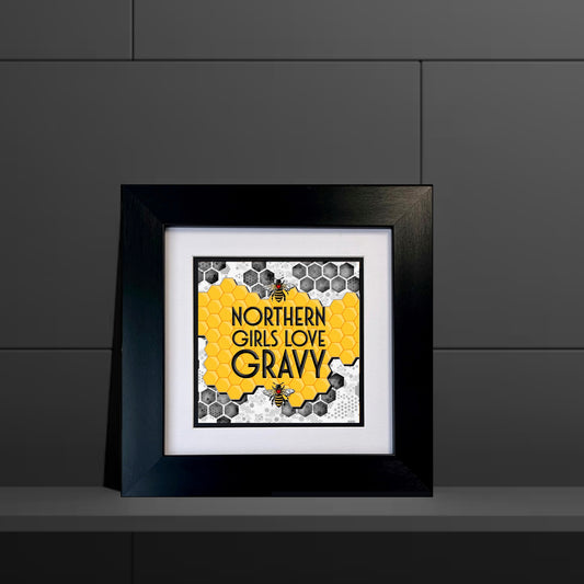 Framed artwork with 'Northern Girls Love Gravy' text on a honeycomb pattern against a dark gray background.