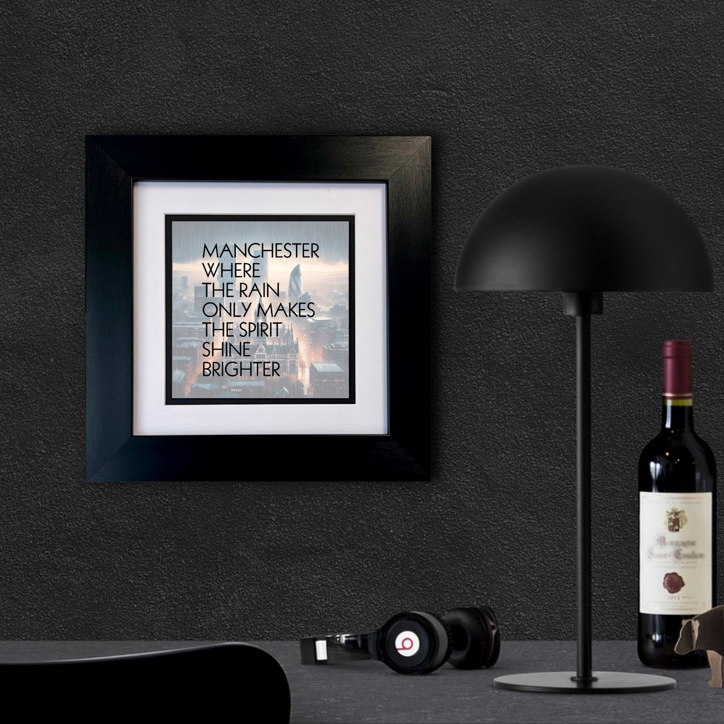 A FRAMED  print with the text 'MANCHESTER WHERE THE RAIN ONLY MAKES THE SPIRIT SHINE BRIGHTER', featuring an image of a cityscape in the background.