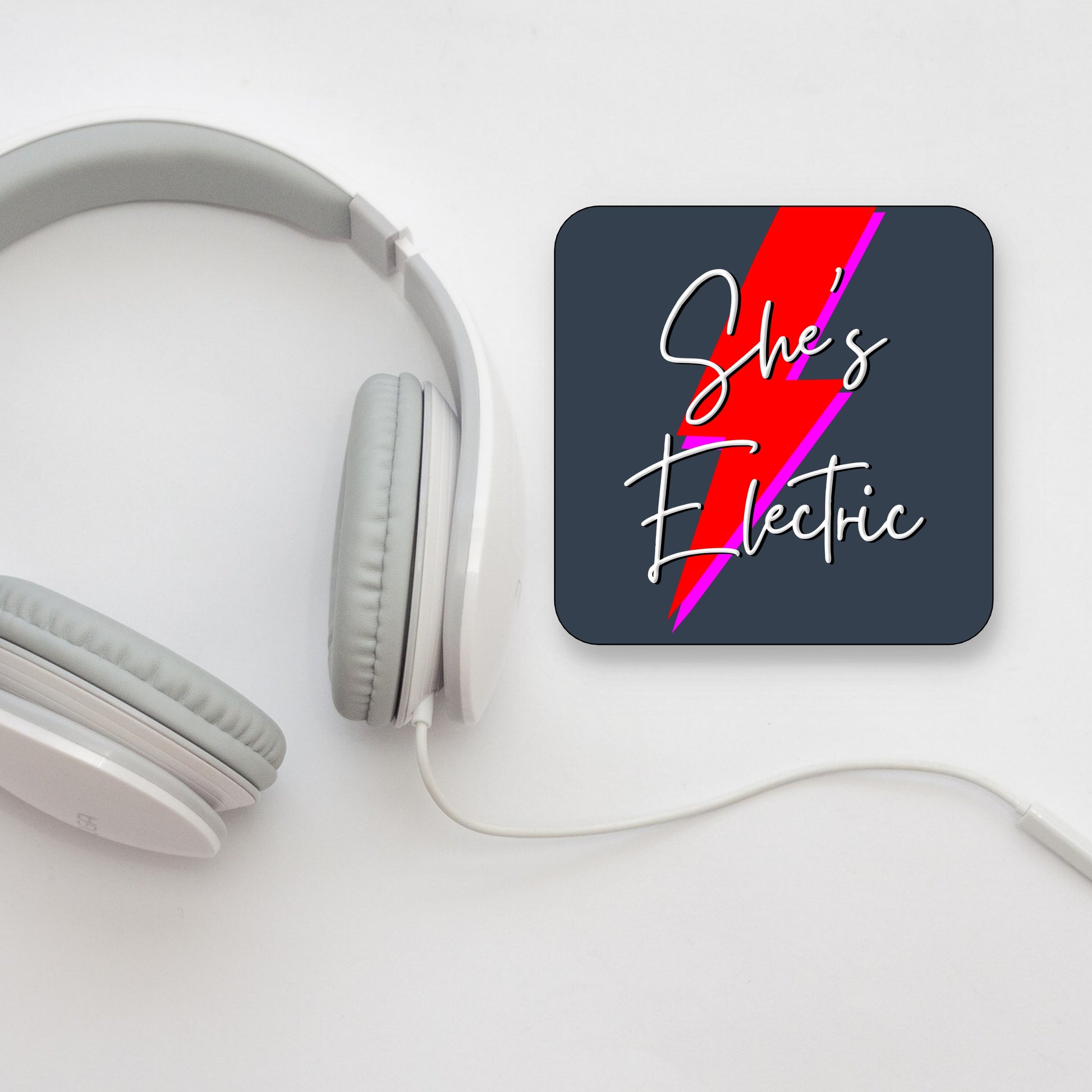 A square coaster with a gloss finish, featuring the text 'She's Electric' with a red lightning bolt design on a dark background. OASIS LYRICS