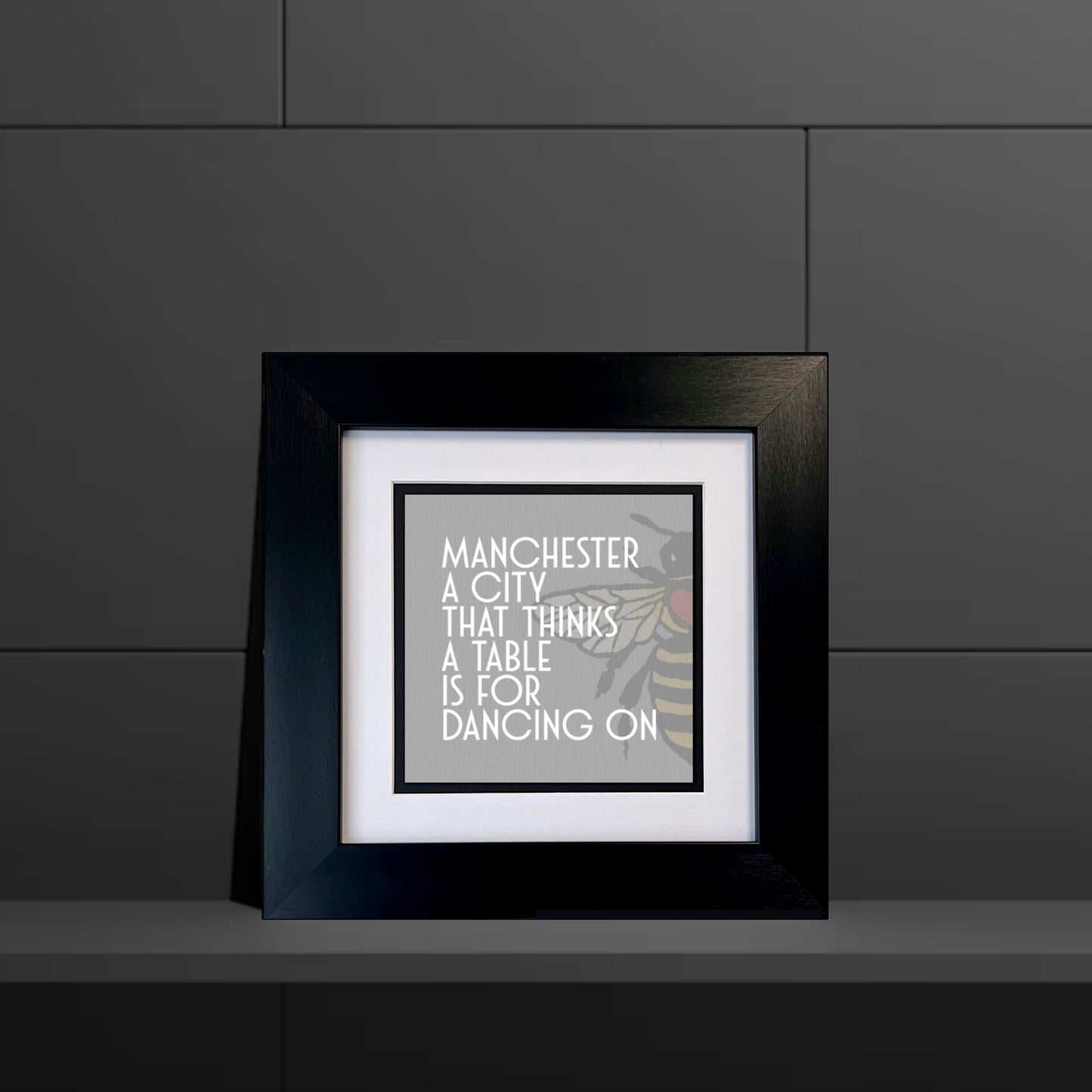 MANCHESTER A CITY THAT THINKS A TABLE IS FOR DANCING ON FRAMED PRINT GREY BACKGROUND MANCHESTER BEE